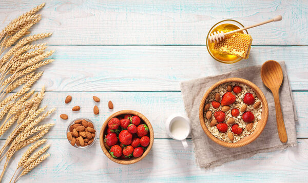 Breakfast with oat flakes, natural milk, fresh strawberry, almonds and honey on rustic background.
