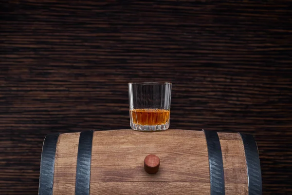 A glass of whiskey on a traditional oak barrel