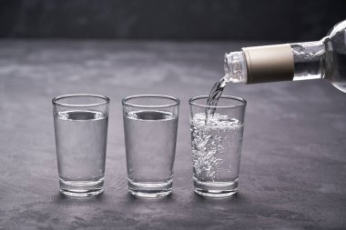 Pouring vodka into the glass on a black background, selective focus clipart
