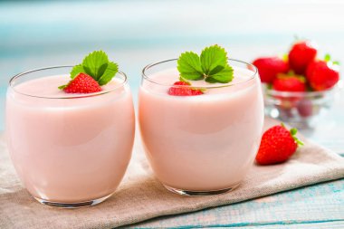 ev yapımı pembe yoğurt turkuaz ahşap arka plan üzerinde çilek ile iki porsiyon