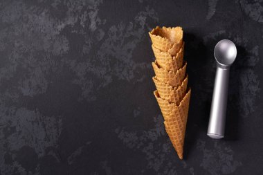 Dondurma için waffle konileri ve siyah arka plan üzerinde bunun için bir kaşık, üst görünümü.
