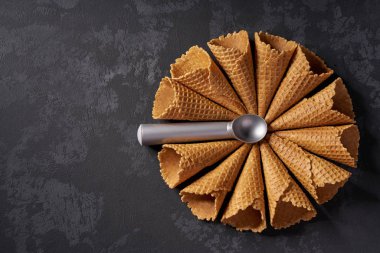 Dondurma için waffle konileri ve siyah arka plan üzerinde bunun için bir kaşık, üst görünümü.