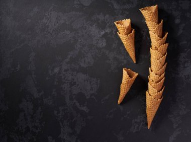 Koyu arka plan üzerinde boş waffle dondurma konileri yığılmış kule natürmort, üst görünümü.