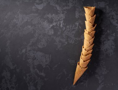 Koyu arka plan üzerinde boş waffle dondurma konileri yığılmış kule natürmort, üst görünümü.