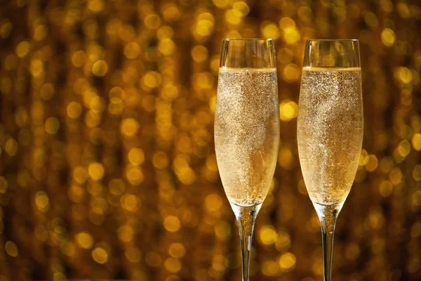 Dois copos de champanhe no fundo dourado do bokeh — Fotografia de Stock