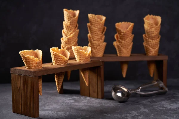 Cones de waffle para sorvete e uma colher para ele no fundo preto com espaço de cópia . — Fotografia de Stock