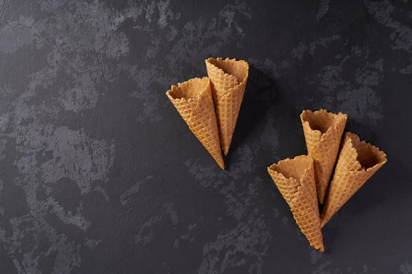 Five sweet wafer cones on a black background.