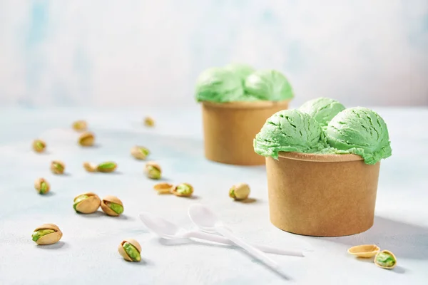 Dos porciones de helado de pistacho en taza de papel sobre fondo de colores menta, enfoque selectivo — Foto de Stock