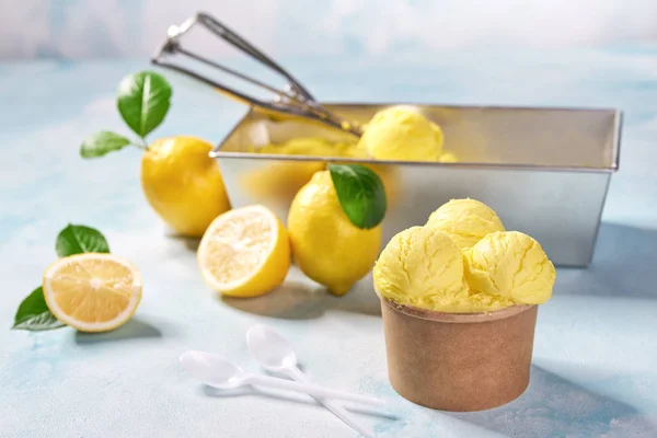 민트 색상 배경에 종이 컵에 레몬 아이스크림 및 신선한 레몬 — 스톡 사진