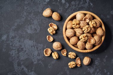 Kopya alanı ile siyah arka plan üzerinde ahşap kase ceviz. Üstte görüntü