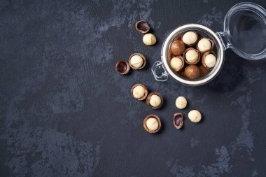 Macadamia siyah bir masa üzerinde açık bir cam kavanozda fındık, kopya alanı ile. Üstte görüntü.