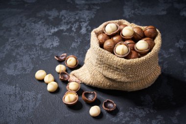 Siyah taş arka plan üzerinde çanta macadamia fındık. Macadamia fındık yığını veya yığını.