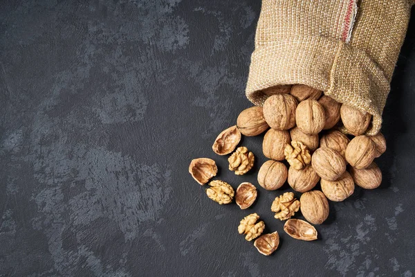 Valnöt i påse på svart bakgrund med kopierings utrymme. Uppifrån och. — Stockfoto