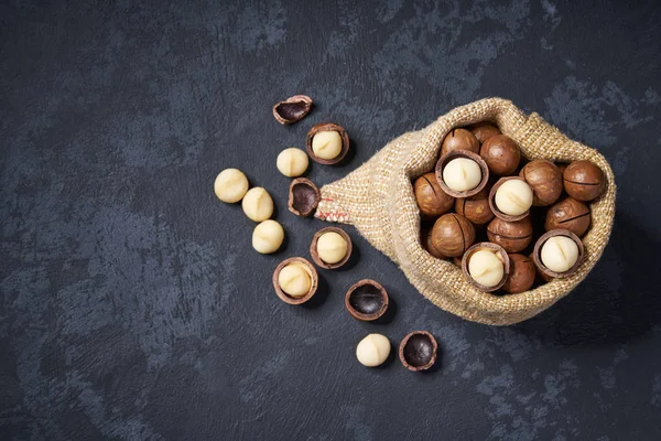 Macadamianötter i påse på svart bakgrund med kopierings utrymme. Uppifrån och. — Stockfoto