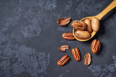 Siyah masa üzerinde tahta kaşıkta Pekan, kopya alanı ile. Üstte görüntü.