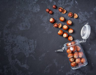 Siyah masa üzerinde açık cam kavanozda fındık, kopya alanı ile. Üstte görüntü.