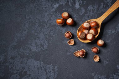 Siyah masa üzerinde tahta kaşık fındık, kopya alanı ile. Üstte görüntü.