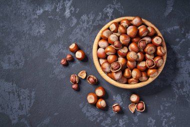 Kopya alanı ile siyah arka plan üzerinde ahşap kase fındık. Üstte görüntü.