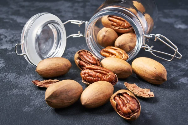 Pecan i en öppen glasburk på svart bord, närbild. — Stockfoto