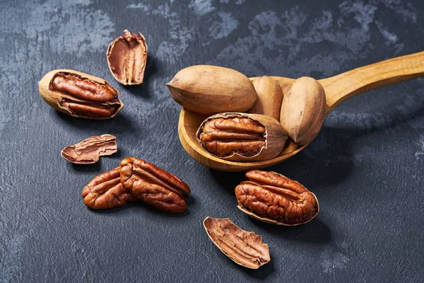 Pecan em colher de madeira na mesa preta, close-up . — Fotografia de Stock