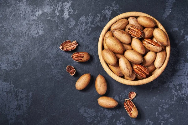 Pecan i träskål på svart bakgrund med kopierings utrymme. Uppifrån och — Stockfoto