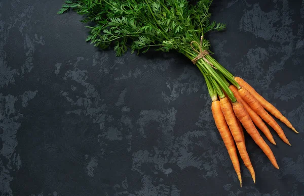Bouquet de carottes fraîches sur fond noir, vue de dessus . — Photo