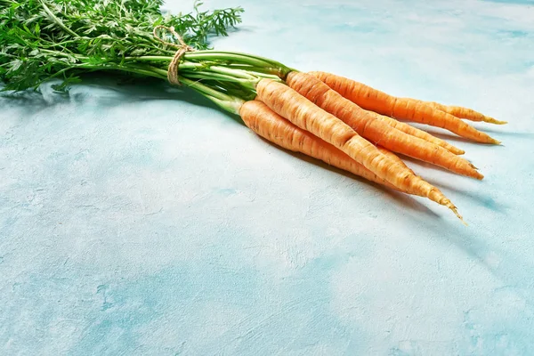 Carottes bio fraîches aux feuilles vertes dans une table turquoise, avec — Photo