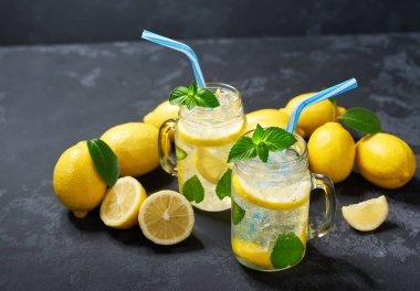 Taze limon ile siyah bir arka plan üzerinde kavanozlarda ferahlatıcı soğutulmuş limonata. Üstte görüntü