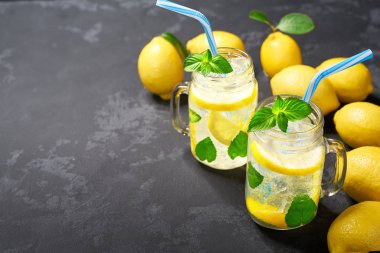 Taze limon ile siyah bir arka plan üzerinde kavanozlarda ferahlatıcı soğutulmuş limonata. Üstte görüntü