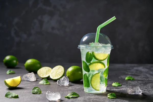 Zimny orzeźwiający Mojito w plastikowym przezroczystej filiżance na czarnym grzbiecie — Zdjęcie stockowe