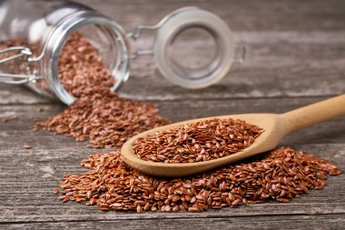 Keten tohumları cam bir kavanozdan tahta bir kaşığa dökülür.