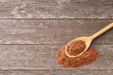 Kırsal bir arka planda tahta kaşıkta çiğ keten tohumu. Üst görünüm.