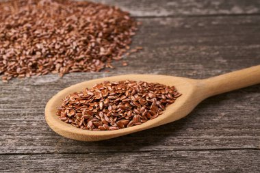 Kırsal bir arka planda tahta kaşıkta çiğ keten tohumu..