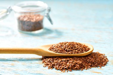 Tahta kaşıkta keten tohumu ve kırsal bir masada açık cam kavanoz..