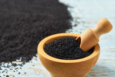 Mavi ahşap arka planda ahşap bir kasede siyah kimyon..