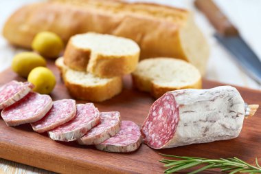 Geleneksel İspanyol Fuet ince kurutulmuş sosis tahta üzerinde dilimler zeytin ve ekmeğin yanında.