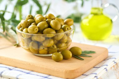 Lezzetli yeşil zeytinler beyaz bir masada cam kasede..