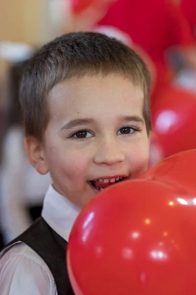 little funny boy with red balloon. portrait of a funny kid holding a big red balloon against an abstract background.