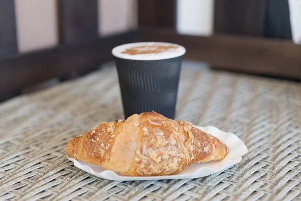 Kaffe att gå i en pappersmugg med croissanter på träbord. Kaffe att gå i en pappersmugg med croissanter, närbild. selektivt fokus — Stockfoto