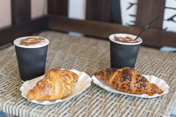 Cappuccino mit Croissant. Zwei Tassen Kaffee mit Milchschaum stehen auf einem Tisch in der Cafeteria. zwei Tassen Kaffee und zwei Croissants auf der Straße im Croissant-Café. Inschrift auf Tasse - Croissant Café — Stockfoto