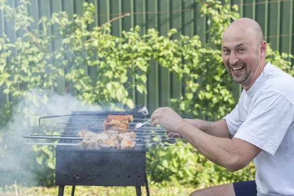 Yakışıklı adam Barbekü arkadaşlar için hazırlanıyor. Genç çift kendi bahçesinde barbekü yapma
