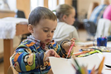 Küçük çocuk bir kağıt makas ile kesme. Koyu kahverengi saç kesme kağıt makas ile kesme ile şirin küçük çocuk.