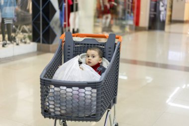 Hangi çocuk oturur ürünleri ile bir arabası. Tam sepeti süpermarket gıda ile. Bir bebek arabasında oturur.