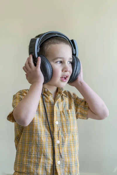 Четырехлетний Мальчик Рубашке Внимательно Слушает Музыку Больших Черных Наушниках Маленький — стоковое фото