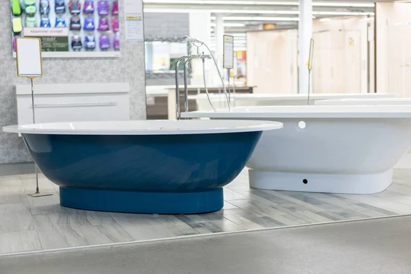 blue bath in the store. hite bath in the building store. baths in the plumbing store. Sanitary engineering shop. White bathrooms. shop baths. Plumbing. new baths. Bathroom on beautiful forged legs.