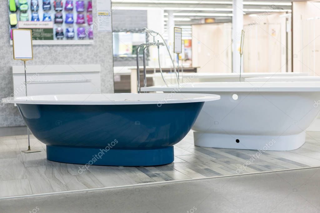 blue bath in the store. hite bath in the building store. baths in the plumbing store. Sanitary engineering shop. White bathrooms. shop baths. Plumbing. new baths. Bathroom on beautiful forged legs.