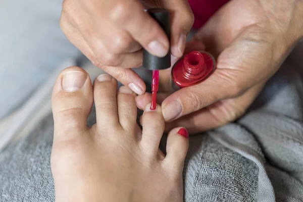Asıl müşteri çivi ile vernik kapsar. Eldiven umurunda hakkında bir kadının ayak tırnakları eller. Pedikür, manikür güzellik salonu konsept. Kırmızı renkli vernik çivi