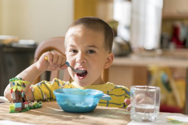 Çocuk 4 yıl püresi yiyor. Çocuk tablo. Çocuğun bağımsızlık kavramı. Çocuk bir iştahla mutfak arka planda breakfasting.