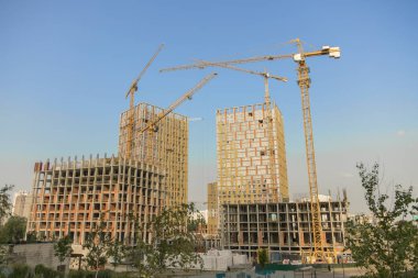 Hoisting crane and new multi-storey building. ndustrial background. Construction of high-rise houses and hoisting tower cranes. New multi-storey housing and large crane. clipart