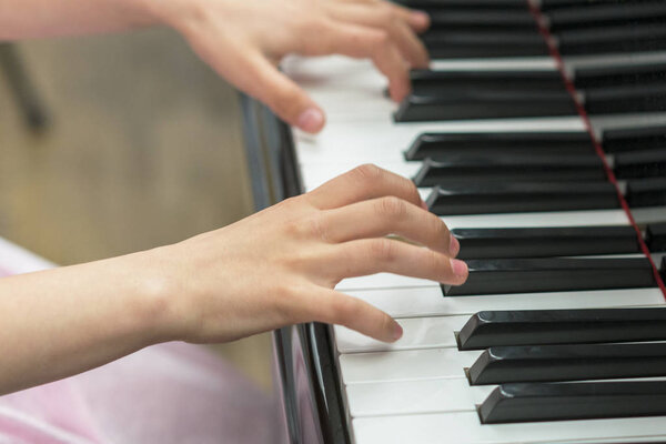 childrens hands are playing the piano. Childs hand on piano keys.